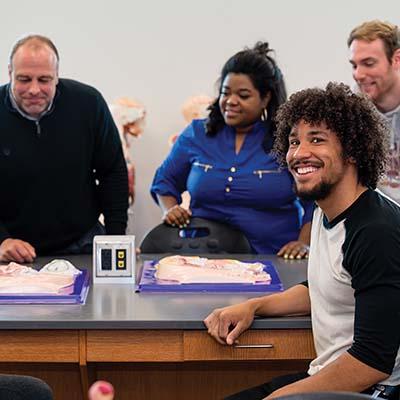 Male Student with other students and professor in classroom